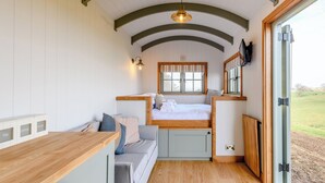 Une pièce confortable avec un lit, un canapé, un comptoir en bois et une fenêtre donnant sur l’extérieur.