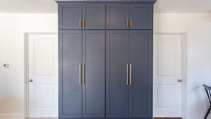 Un armario grande de color azul oscuro con tiradores dorados en una habitación con paredes blancas y suelo de madera.