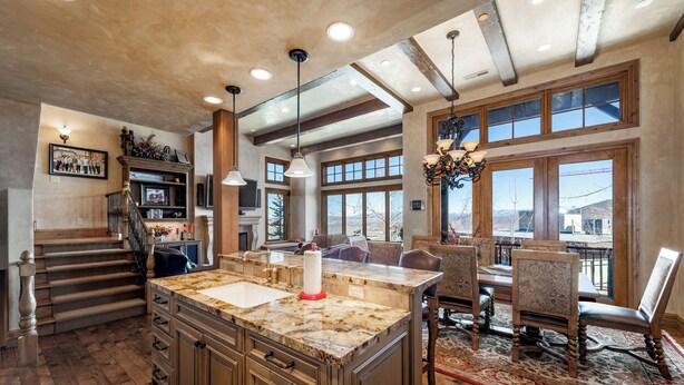 A spacious kitchen with a large island, wooden cabinets, and a dining area with a chandelier.