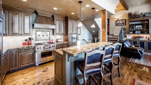 A spacious kitchen with wooden cabinets, a large island, and a dining area with leather chairs.