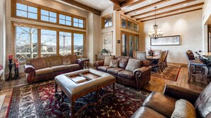 A spacious living room with large windows, a fireplace, and a dining area.