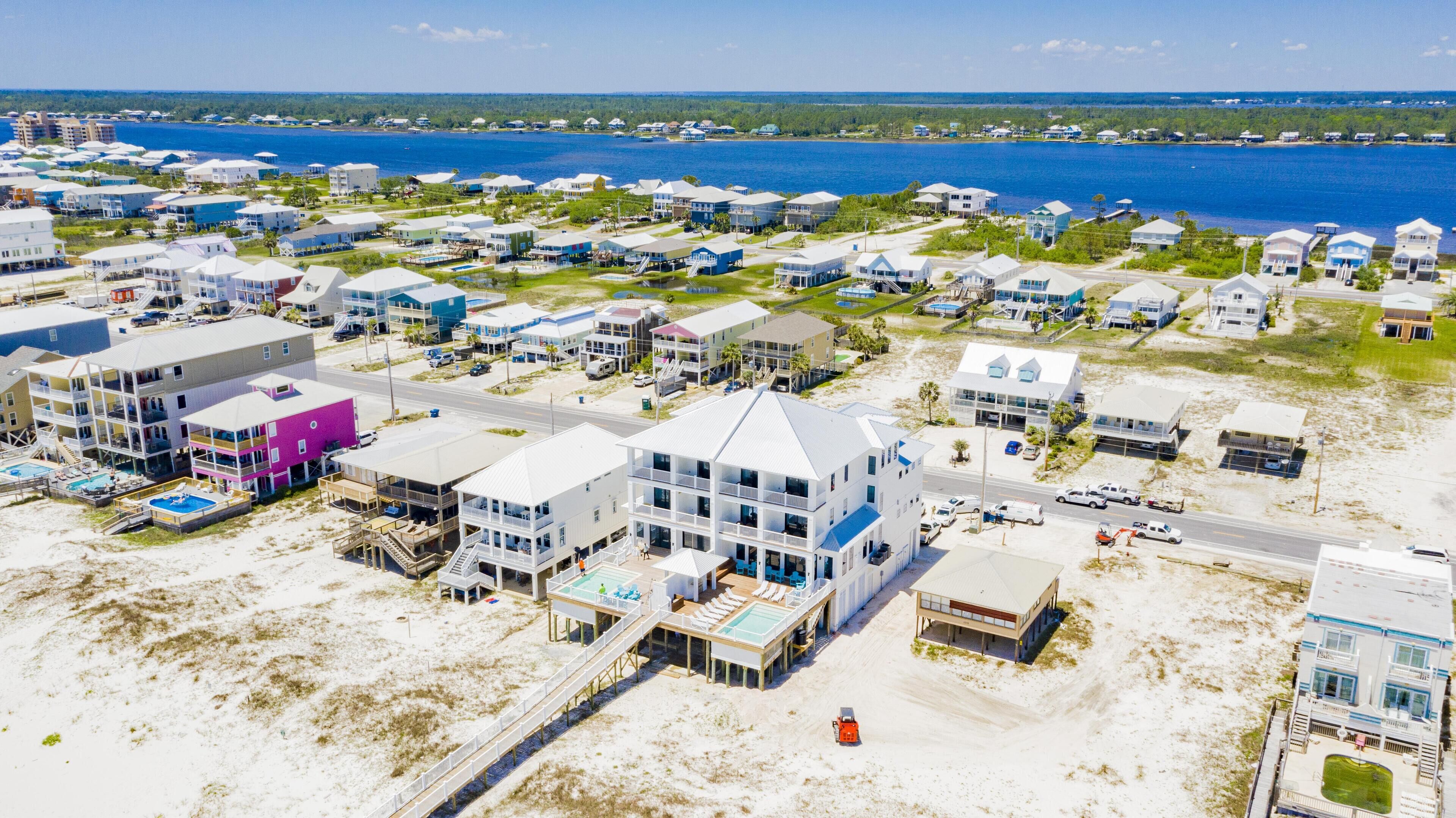 An aerial view of a coastal residential area with multiple two-story buildings, a beach, and a clear view of the ocean.