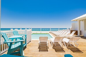 Une terrasse avec des chaises longues et une piscine, offrant une vue sur l’océan.