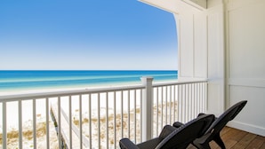 A beach view from a covered porch with white railings and two wicker chairs. - Seaside East and West ( 2 Properties - 24 Bedrooms) (Gulf Shores)