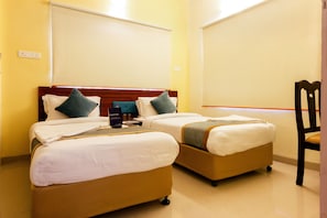A hotel room with two single beds, a wooden headboard, and a chair.