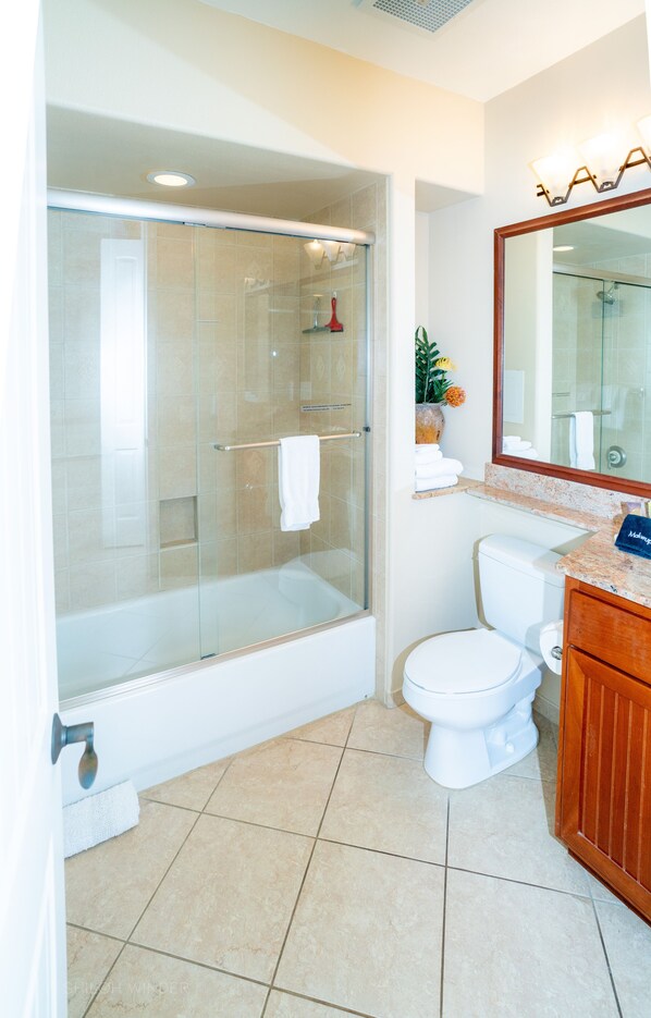 A modern bathroom with a glass-enclosed shower, a white toilet, and a wooden vanity.