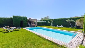A rectangular swimming pool with a wooden deck, surrounded by well-maintained grass and hedges. - Alegría de Ronda by Ruralidays (Málaga)