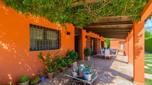 An outdoor patio area with a table and chairs, surrounded by potted plants and a pergola. - Alegría de Ronda by Ruralidays (Málaga)