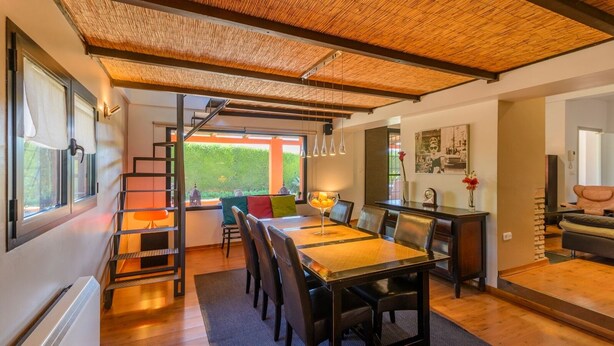 A modern dining area with a wooden table, chairs, and a staircase leading to a balcony. - Alegría de Ronda by Ruralidays (Málaga)