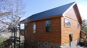 Eine Blockhütte mit Steinunterbau, einem Balkon und einem Metalldach.