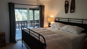 A bedroom with a bed, a nightstand, a lamp, a window with curtains, and a view of the outdoors. - NORTH LAKE TAHOE VACATION RENTAL WITH SKI AND MOUNTAIN VIEWS, HIKE & BIKE TRAILS (Incline Village)