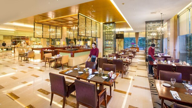 A spacious restaurant with multiple dining tables and chairs, a bar area, and a view of the outdoors. - Kingdom Narada Grand Hotel Yiwu (Jinhua)