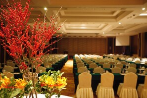 A banquet hall with rows of tables, chairs, and a floral centerpiece. - Kingdom Hotel Yiwu (Jinhua)