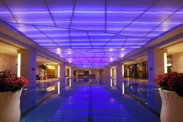 A hotel corridor with a reflective floor and a ceiling with blue lighting.