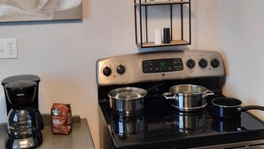 A kitchen with a stove, pots, a coffee maker, and a decorative wall piece above the stove. - Charming Fruitland Park Getaway (Fruitland Park)