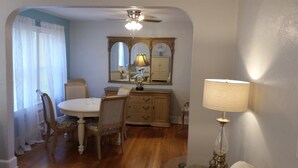 A dining area with a round table, chairs, a wooden cabinet, and a mirror above it. - Charming Fruitland Park Getaway (Fruitland Park)