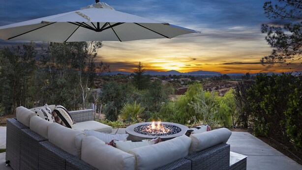 A patio with outdoor furniture, a fire pit, and a view of a sunset over a landscape. - WOW! Luxury Wine Country Estate - 6 Bedrooms • Hot Tub • Game Room (Temecula)