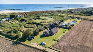 An aerial view of a coastal area with houses, a beach, and a rocky breakwater. - 1 bedroom accommodation in Happisburgh (Happisburgh)