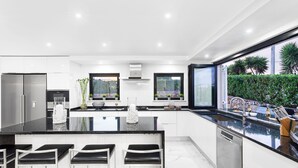 A modern kitchen with a large island, bar stools, and a view of the garden. - Seafront View next to the famous “Benagil Caves” (Lagoa)