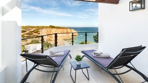 A balcony with two lounge chairs, a small table, and a potted plant. - Seafront View next to the famous “Benagil Caves” (Lagoa)