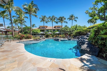 Lagoon style pool surrounded by palms, sun loungers, and lava rock features.