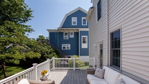 A deck with a white railing, wicker furniture, and a flower vase. - Main Street Livin’ (Flemington)