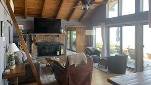 Ein gemütliches Wohnzimmer mit Kamin, bequemen Sitzgelegenheiten und einem Fernseher.