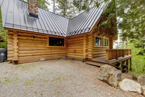 Una baita di legno con tetto in metallo, un patio e terreno sterrato.