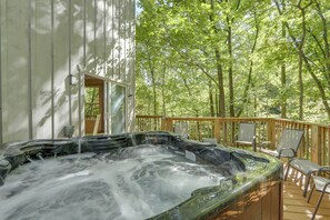 Un bain à remous sur une terrasse en bois, entouré d’arbres.