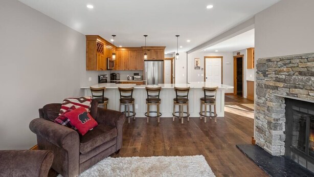 A modern kitchen with wooden cabinets, a central island with bar stools, and a stone fireplace. - Spacious 3 Level 3BR+3Bath Townhouse w/Fireplace (Dover)