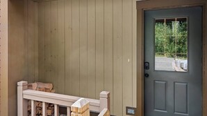 A wooden porch with a white railing, a grey door with a window, and a stack of firewood. - Spacious 3 Level 3BR+3Bath Townhouse w/Fireplace (Dover)