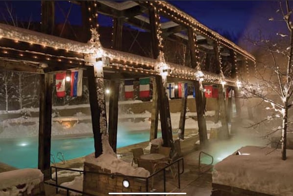 A spa area with a hot tub surrounded by snow-covered trees and a wooden deck.