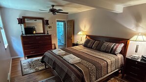 A bedroom with a bed, a dresser, a mirror, a ceiling fan, and two bedside lamps.