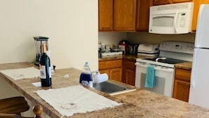 A kitchen with wooden cabinets, a granite countertop, a microwave, a stove, and a refrigerator. - North Getaway Cottage (Williamstown)