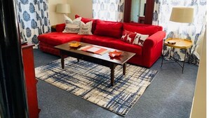 A living room with a red sofa, a wooden coffee table, patterned curtains, and a mirror. - North Getaway Cottage (Williamstown)