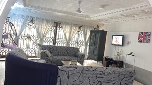Una sala de estar con un sofá estampado, un televisor y un aparador.