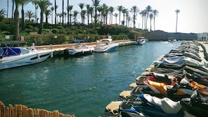 A marina with boats docked along the waterfront, surrounded by palm trees and a rocky shoreline. - Villa - Sleeps 7 - Pool - Parking (Javea)