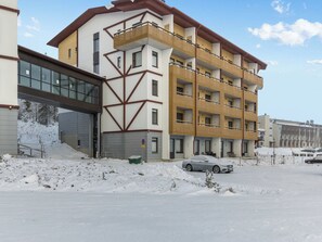 Ein mehrstöckiges Gebäude mit modernem architektonischen Design, das eine Kombination aus Balkonen und Fenstern aufweist.
