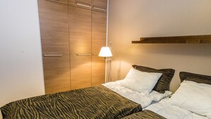 Ein Schlafzimmer mit zwei Betten, einem Holzschrank und einer Nachttischlampe.
