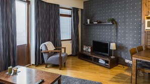 Ein modernes Wohnzimmer mit Flachbildfernseher, Holzmöbeln, einem Couchtisch und einem Essbereich.