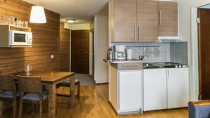Eine kleine Küche mit Holzausstattung, einer Mikrowelle, einer Kaffeemaschine und einem Spülbecken.
