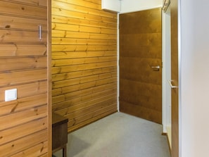 Un couloir étroit, avec un lambris en bois d’un côté et une porte fermée de l’autre.