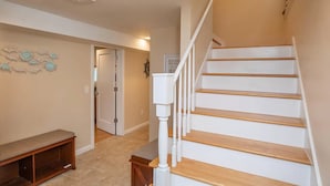 A staircase with white railings and wooden steps, leading to a landing with a bench and a wall-mounted sign.