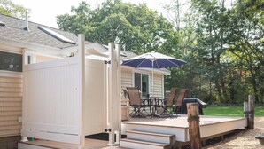 A covered outdoor deck with a table and chairs, a grill, and a covered patio area.