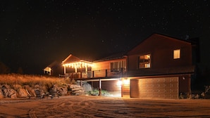 A two-story house with a garage, a balcony, and a well-lit driveway.