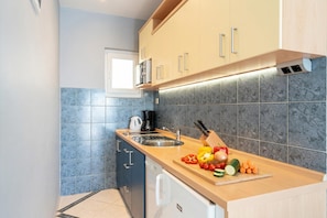 A modern kitchen with a sink, countertop, and a variety of fresh vegetables.
