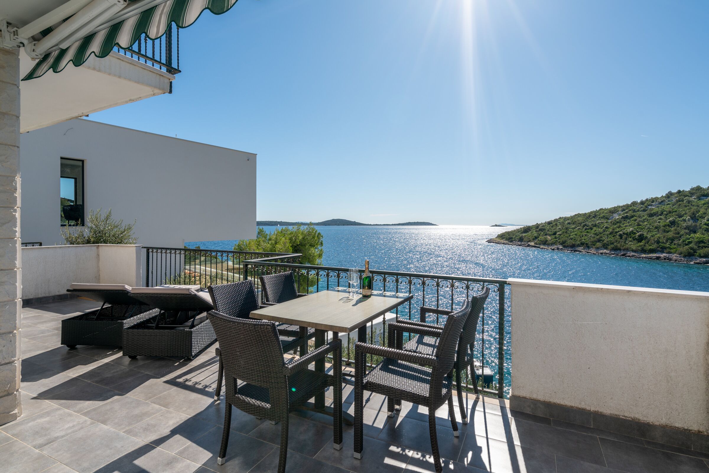 A terrace with a table and chairs overlooking a body of water.