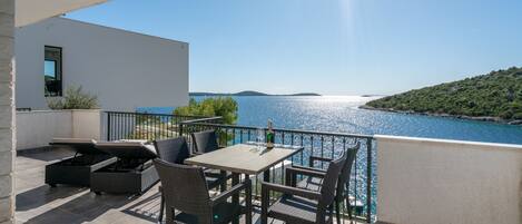 A terrace with a table and chairs overlooking a body of water.