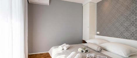 A modern hotel room with a neatly made bed, a magazine, and a flower arrangement.