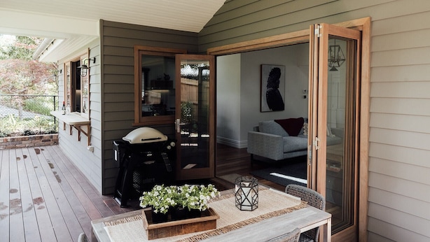A covered porch with a wooden table, potted plants, and a seating area. - Charming Luxury Self Contained Cottage. (Leura)
